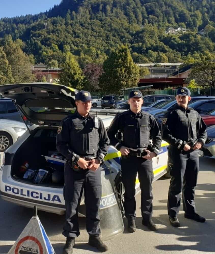 Policisti pred policijskim avtomobilom