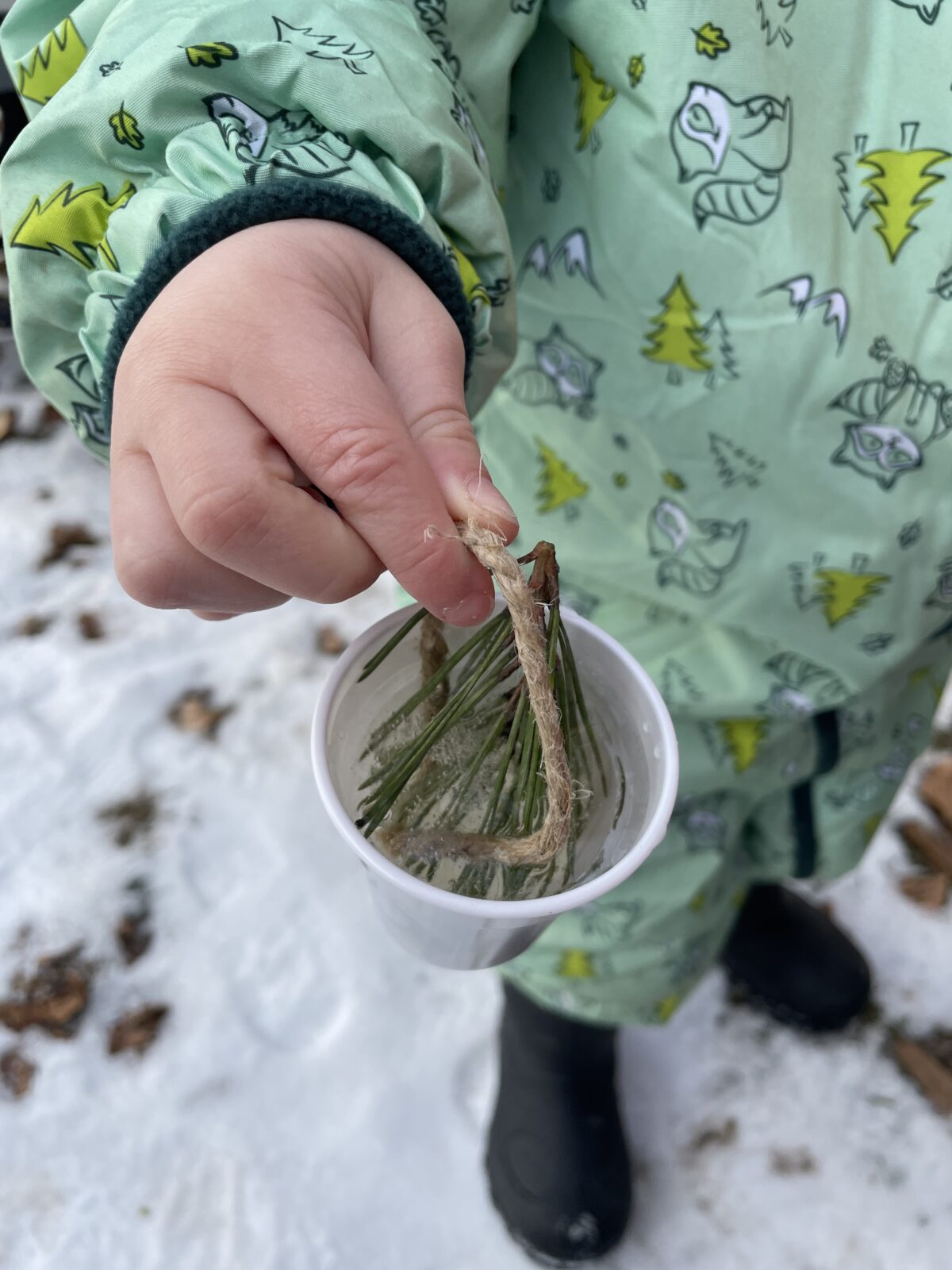 Otroška roka drži vrvico s plastičnim kozarcem z ledom