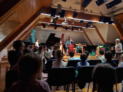 Glasbena pravljica v glasbeni šoli – deček igra na kontrabas, v ospredju otroci