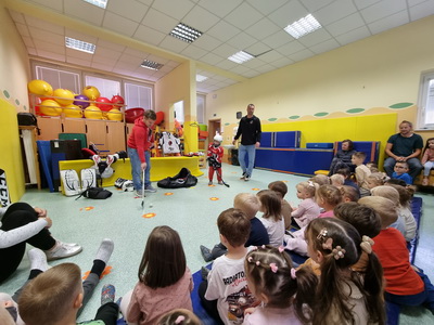 Predstavitev hokeja na ledu - predstavnika z enim otrokom igrata hokej, v ozadju opazujejo otroci Predstavitev-hokeja-na-ledu-predstavnika-z-enim-otrokom-igrata-hokej-v-ozadju-opazujejo-otroci.j